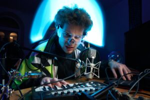 Angry guy plays music with midi keyboard sitting at table in room